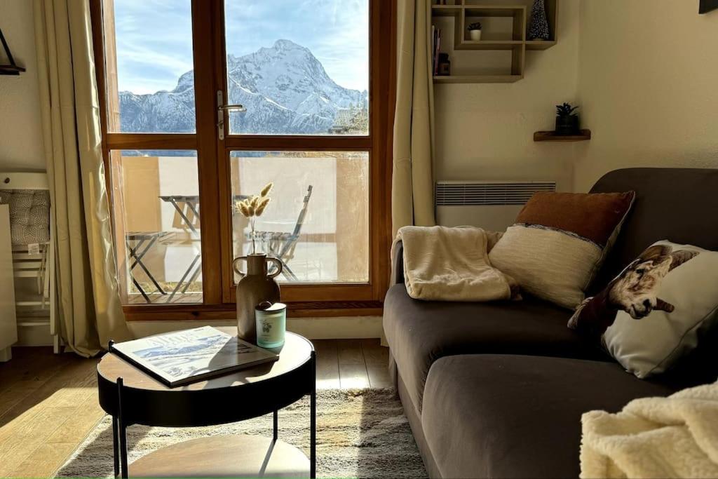 un salon avec un canapé, une table et une fenêtre dans l'établissement Charmant Studio - Vue Montagne - Parking privé, à Les Deux Alpes