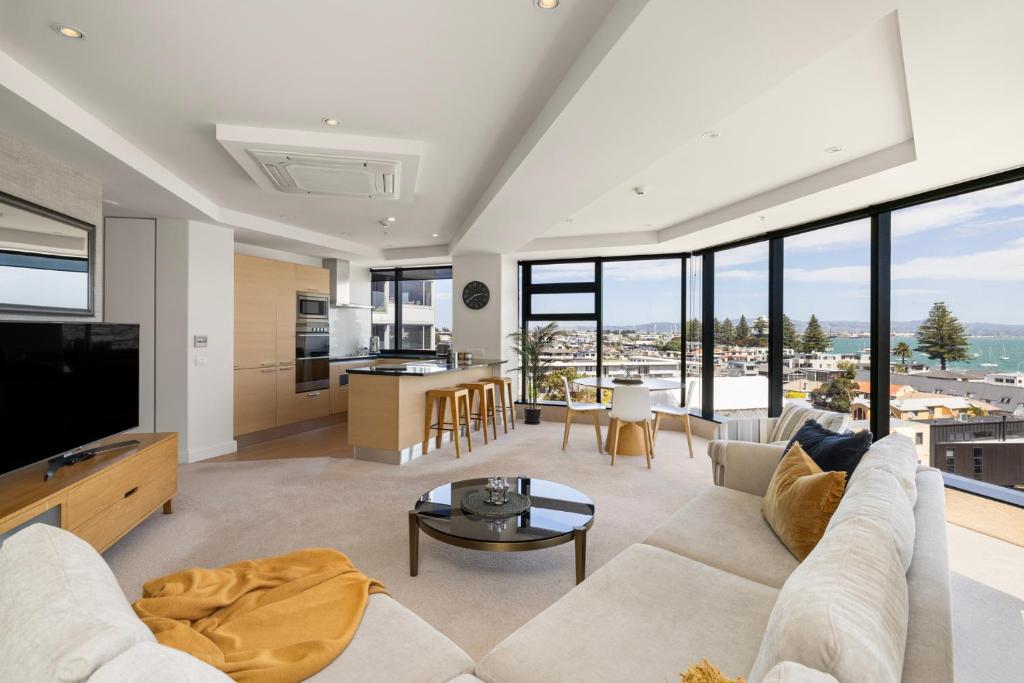 a living room with a couch and a large window at Luxury Ocean & Harbour Views - Heated Pool, Main Beach & Gym in Mount Maunganui