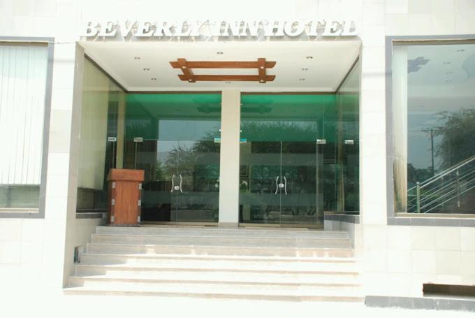 un edificio con un banco de madera delante de él en Beverly Inn Hotel, en Lahore
