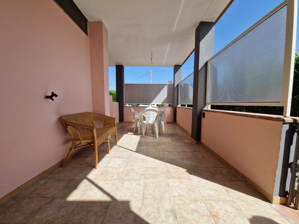 balcón con mesa, sillas y ventanas grandes en Casa Vacanza Alghero, en Santa Maria la Palma