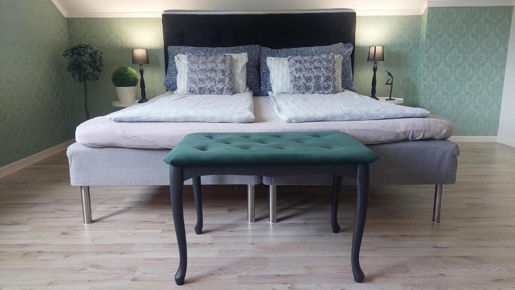 a bedroom with a large bed with a green stool at Øren apartment in Drammen