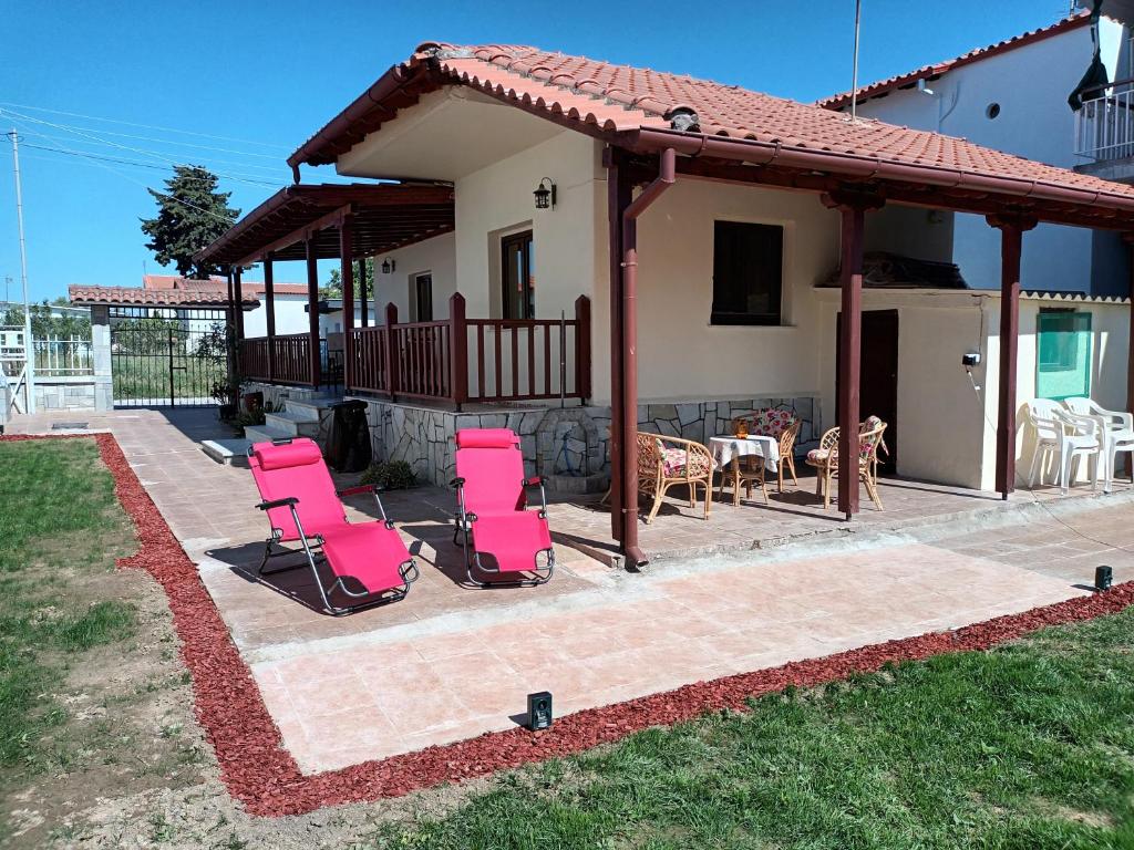 a patio with chairs and tables and a house at Villa Despina in Nea Iraklia