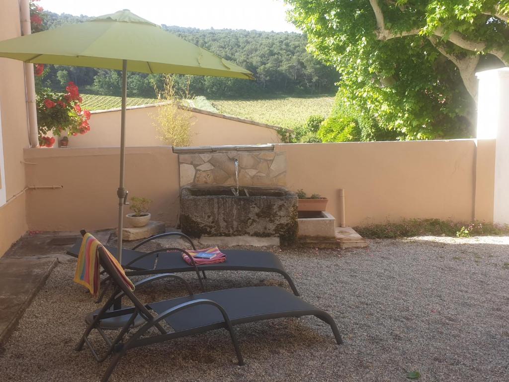 un patio con 2 sillas y una sombrilla en Gîte de la fontaine, en Buisson