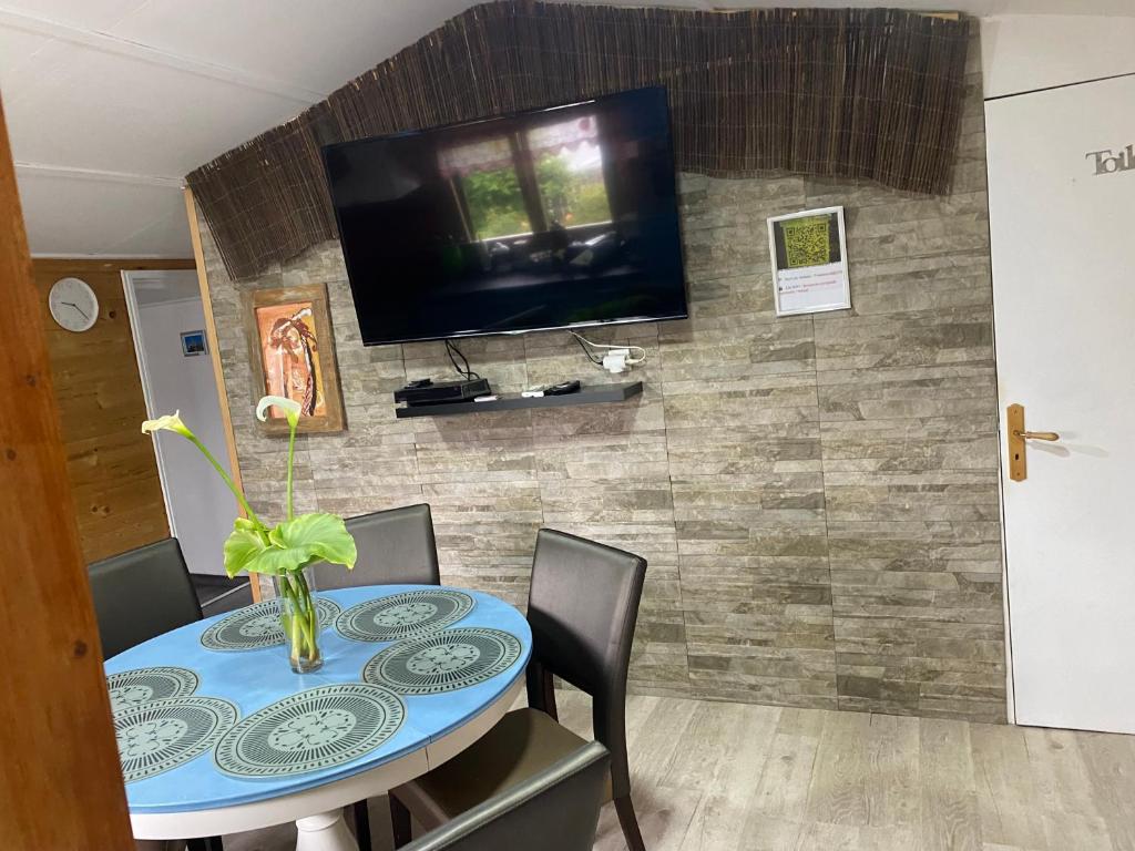 une salle à manger avec une table et une télévision murale dans l'établissement Grand chalet tout équipé 6 personnes proche des plages du débarquement, à Sommervieu