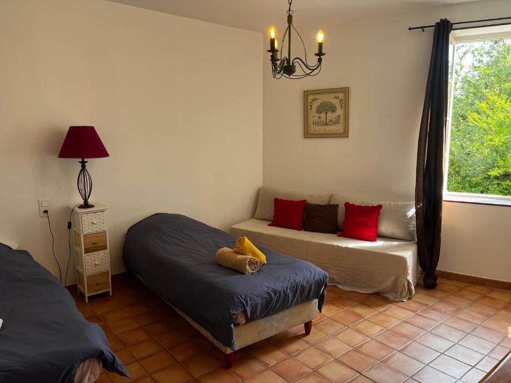 um quarto com 2 camas, um sofá e uma janela em Le Mas de Trévouse em Saint-Saturnin-lès-Avignon