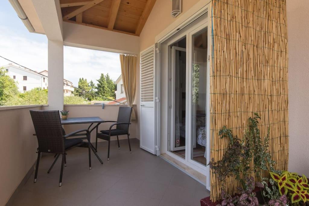 a patio with a table and chairs and a window at Studio Ruzmarin in Krk