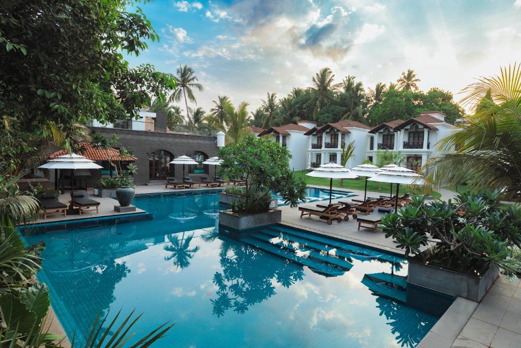 a pool at a resort with tables and umbrellas at Andores Resort And Spa - Calangute in Calangute