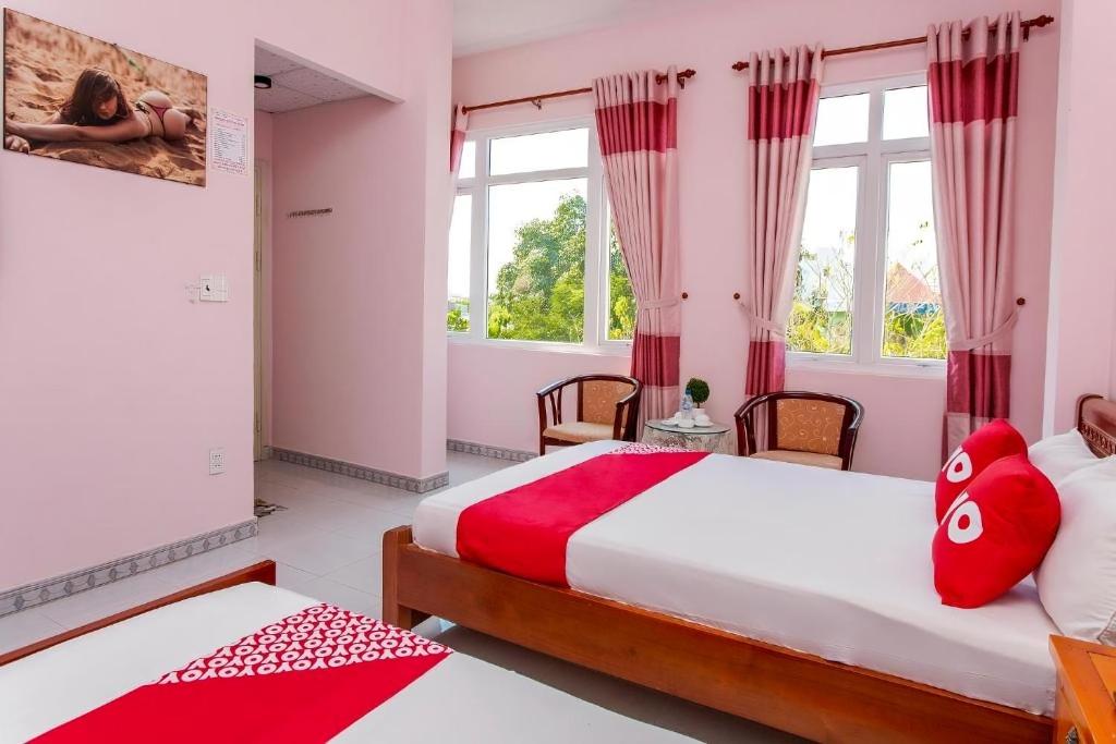 a bedroom with two beds and two windows at Motel Tulip in Da Nang