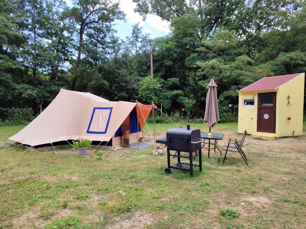 a campsite with a tent and a table and chairs at Familytent "Kukucka" with private sanitary facilities - Holidayfarm Natural Slovakia in Modrý Kameň