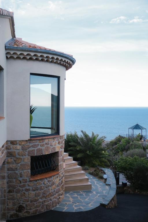 une maison avec une cheminée et l'océan en arrière-plan dans l'établissement Villa d'exception vue mer avec piscine privée, à Saint-Raphaël