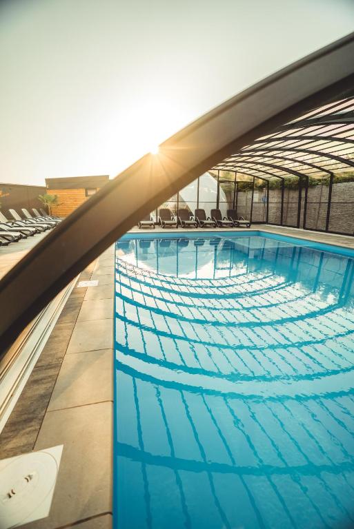 a large swimming pool with chairs on a building at RResort Holiday Homes - HEATED Swimming Pool & Sauna in Rewal