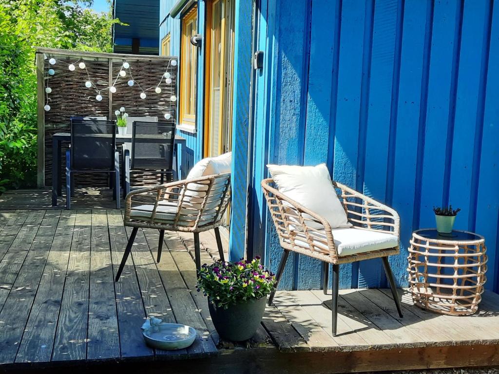 d'une terrasse avec 2 chaises et une table sur un mur bleu. dans l'établissement Ferienhaus "Auszeit mit Herz" im Ferienpark Extertal - Kamin, Fass-Sauna, Massagesessel, à Extertal
