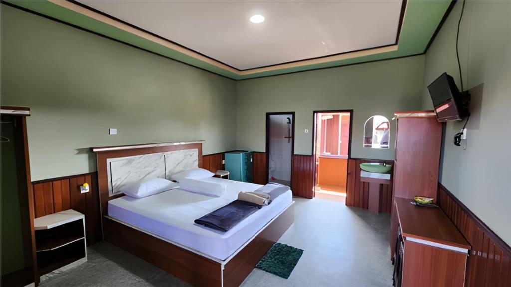 a bedroom with a large bed and a television at Miranda Cottage in Derawan Islands