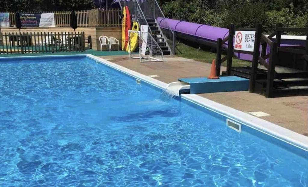 an empty swimming pool with a purple slide in a park at Cosy Cabin - Bideford Bay Holiday Park in Bideford