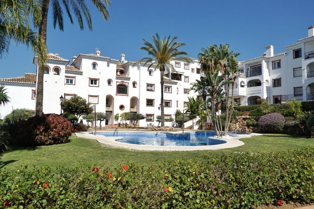 een groot wit gebouw met een zwembad en palmbomen bij Apartamento en Marbella Paraíso al Mar in Marbella