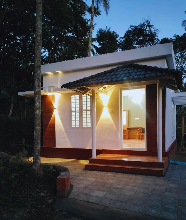 a small white house with a patio at night at Mahogany by Exuberance Stays in Wayanad
