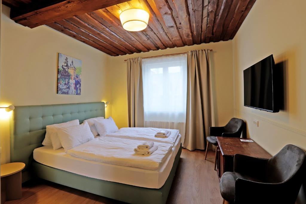Schlafzimmer mit einem Bett, einem Schreibtisch und einem TV in der Unterkunft Hotel Kavalír in Karlsbad