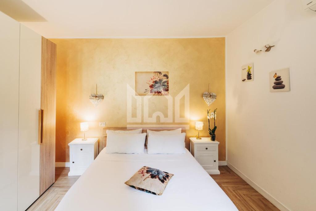 ein Schlafzimmer mit einem weißen Bett und zwei Nachttischen in der Unterkunft Gold Apartment in Ferrara