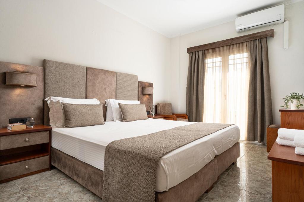 Un dormitorio con una cama grande y una ventana en Hotel Dionysis Studios, en Adamas