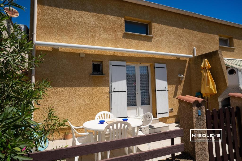 un patio avec une table et des chaises devant un bâtiment dans l'établissement Maison climatisée à 600m de la plage, à Vias