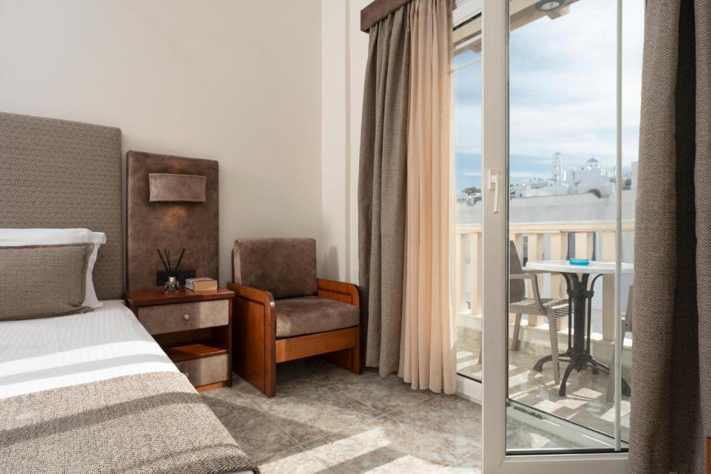 a bedroom with a bed and a chair and a balcony at Hotel Dionysis Studios in Adamantas