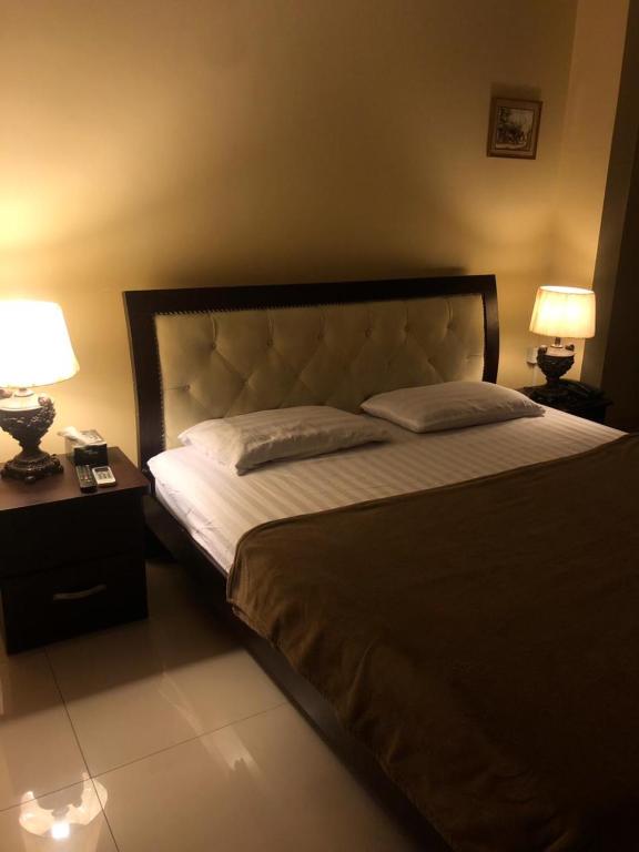 een slaapkamer met een groot bed met 2 lampen bij Holiday Home in Karachi