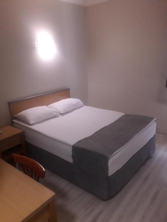 a bedroom with a bed and a desk and a table at OTEL AMİLLER in Erzurum