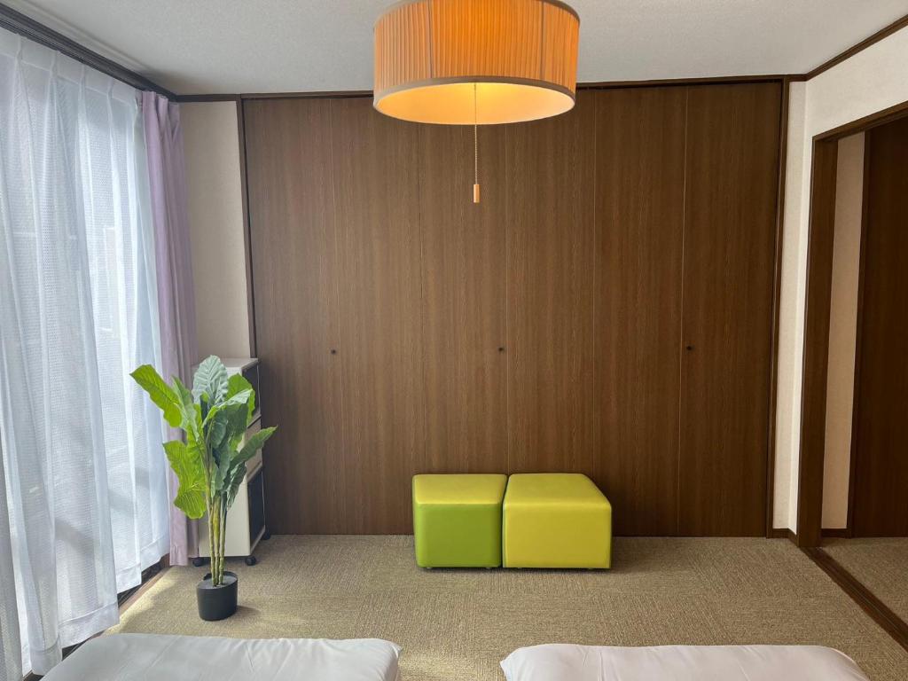 1 dormitorio con 2 camas y un taburete amarillo en 南名駅貸切一軒家, en Nagoya