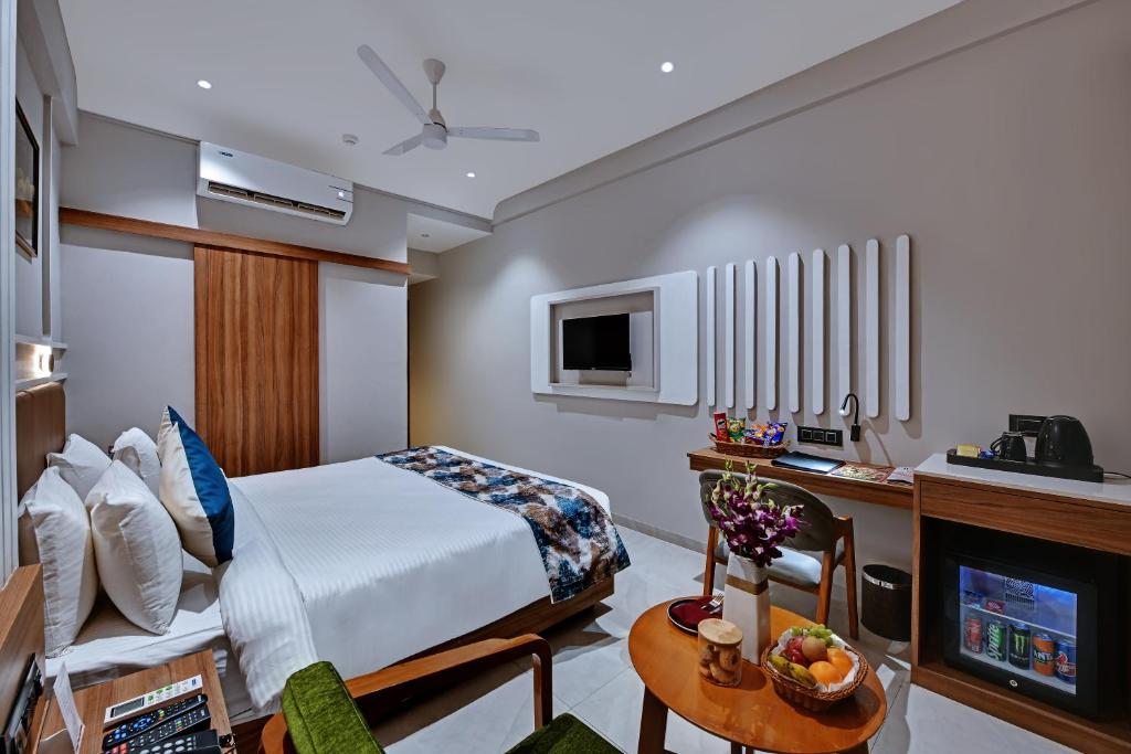 a hotel room with a bed and a tv at Regenta Inn Motikhavdi Jamnagar in Jamnagar