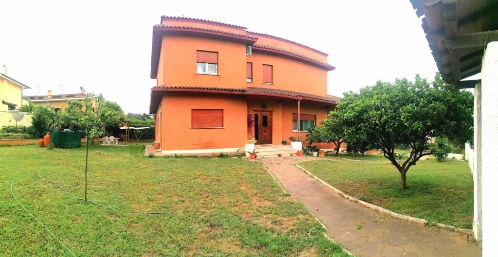 una casa grande de naranja con un árbol en un patio en Da Piero e Gina, en Palidoro