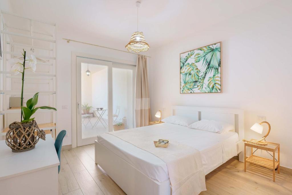 um quarto branco com uma cama e um vaso de plantas em Domo Green House em Villasimius