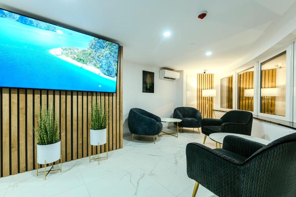 een wachtkamer met stoelen en een grote tv aan de muur bij Hotel Tříška in Brandýs nad Labem