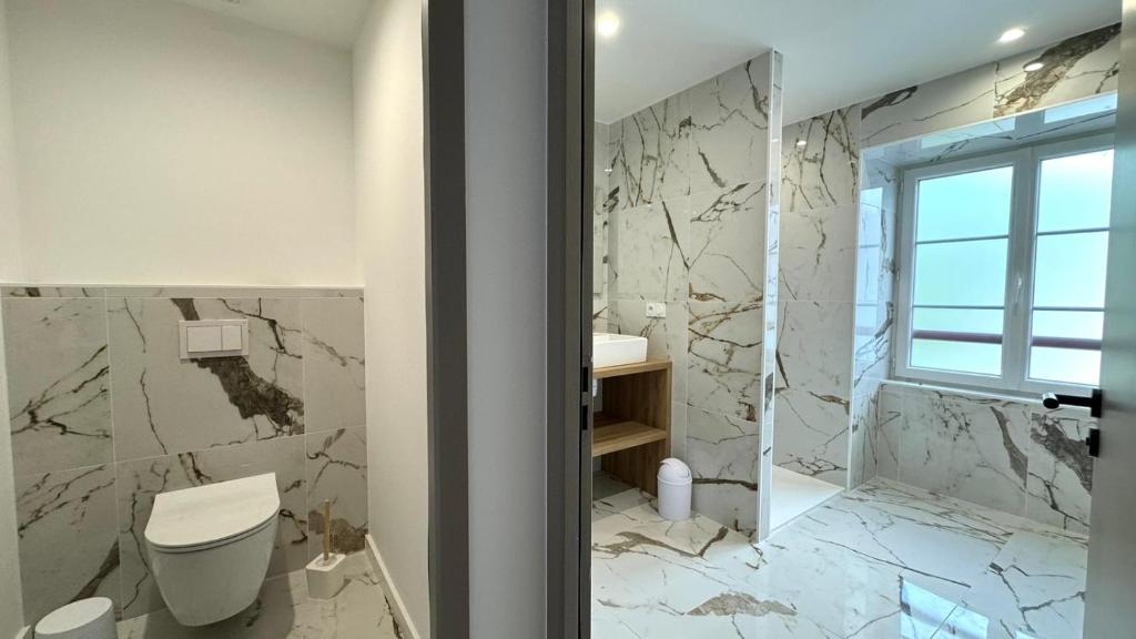 a bathroom with a toilet and a marble wall at Maison LAURENTZENIA in Saint-Jean-Pied-de-Port