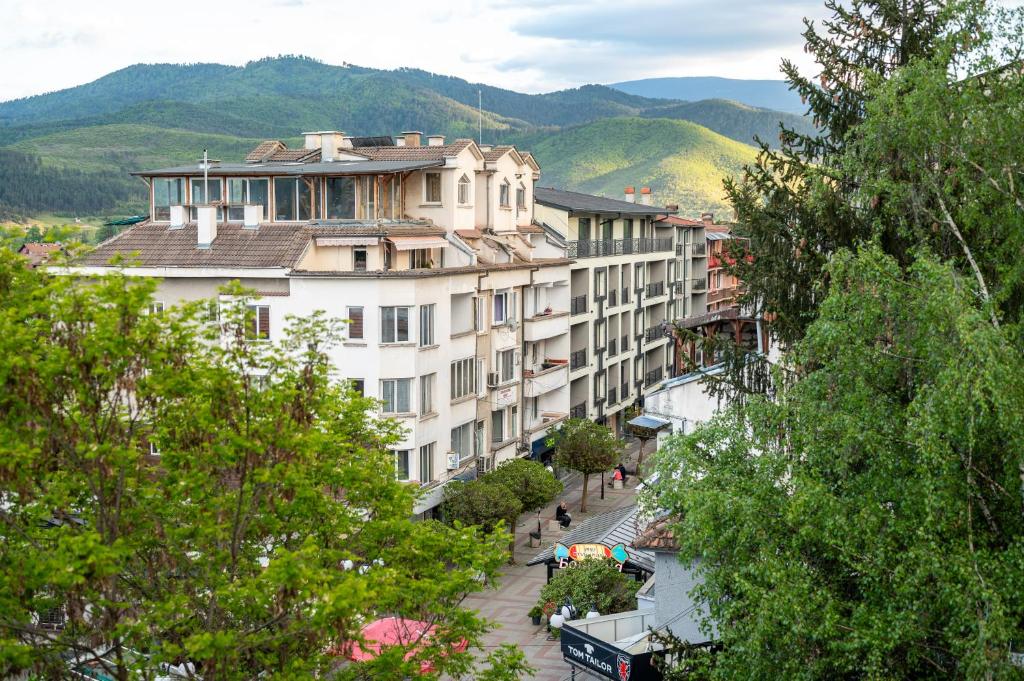 a large white building on a street with trees at Апартамент за гости ВениАн in Velingrad