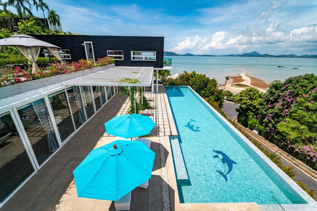 an infinity pool with two blue umbrellas and the ocean at 宛如梦境 一线海景6卧室别墅 超大私人泳池 免费早餐接机 私人影院健身房 in Phuket