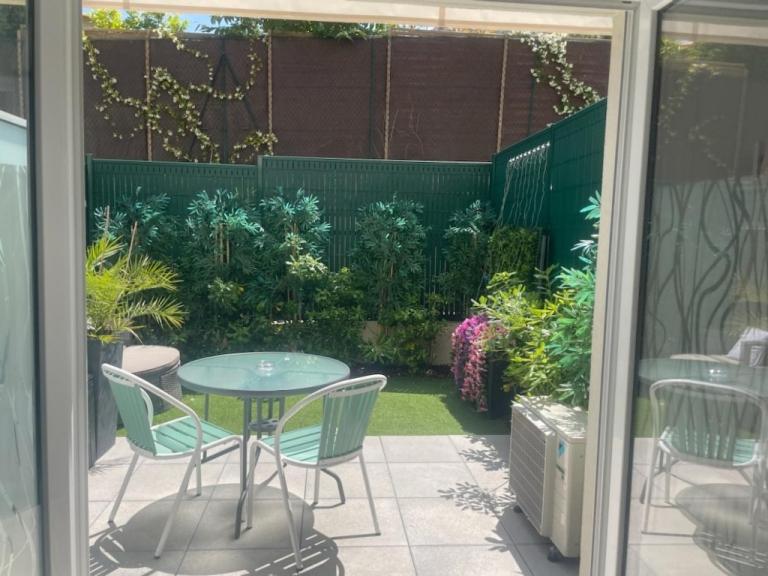 un patio avec une table, des chaises et des plantes dans l'établissement Chez Candie, à La Trinité