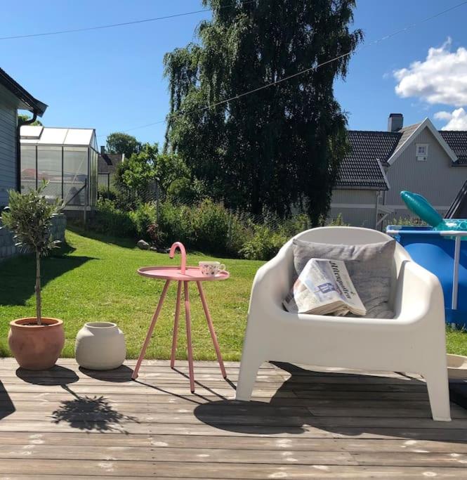 a chair and a table with a newspaper on a patio at Koselig hus med stor og solrik hage in Lillehammer