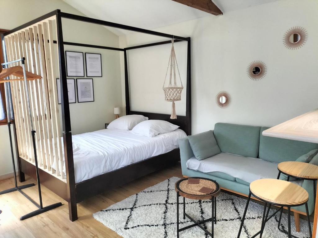 een slaapkamer met een bed en een bank bij Coin de Paradis in Saint-Leu-la-Forêt