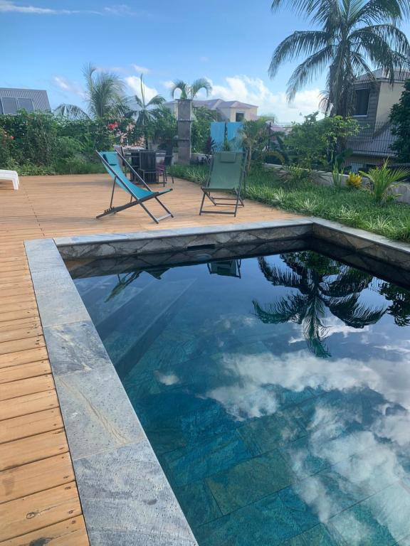 a swimming pool with two chairs and a table at Manapany and Rose in Le Butor