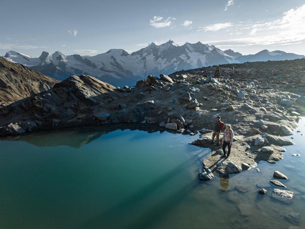 a man standing on top of a mountain next to a lake at Sunshine in Saas-Grund