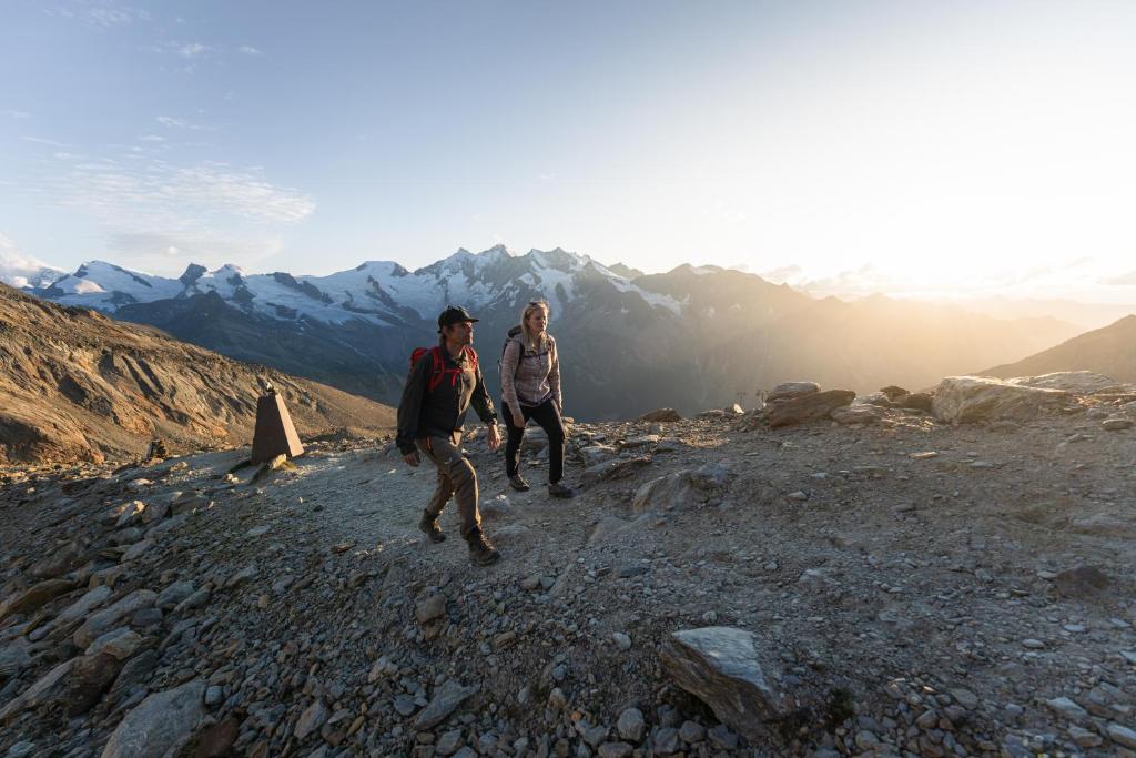 two people walking on a rocky mountain at Sunshine in Saas-Grund
