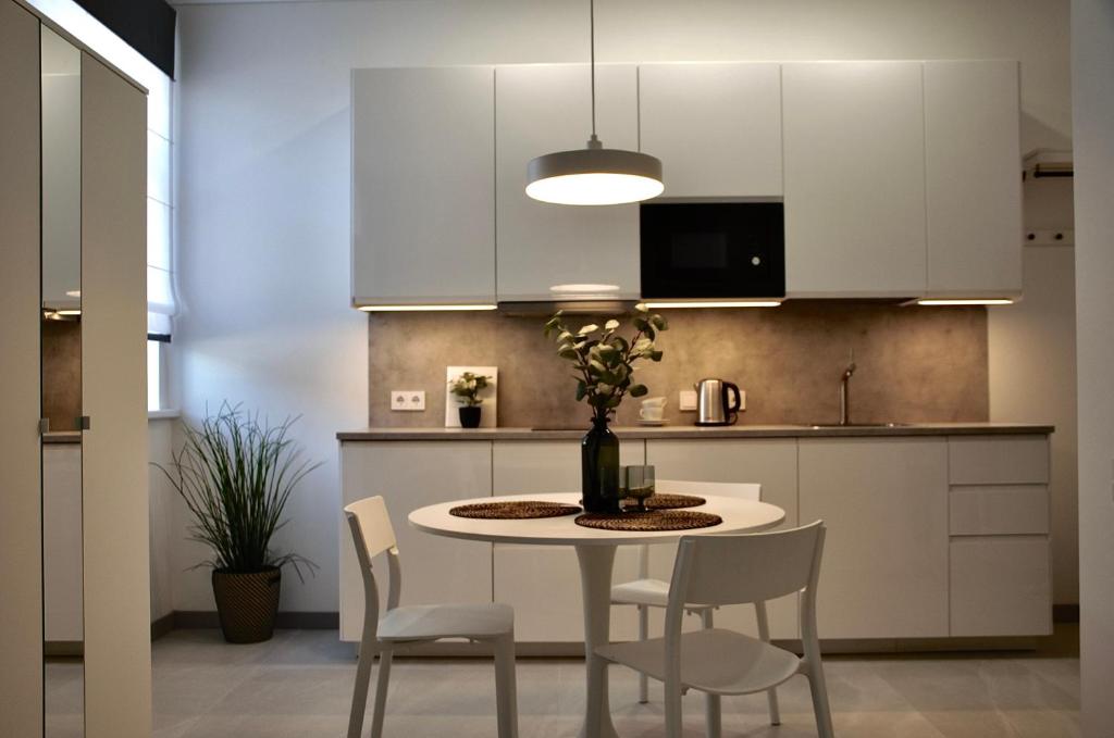 a kitchen with white cabinets and a table and chairs at Mazvydo studio appartment in Klaipėda