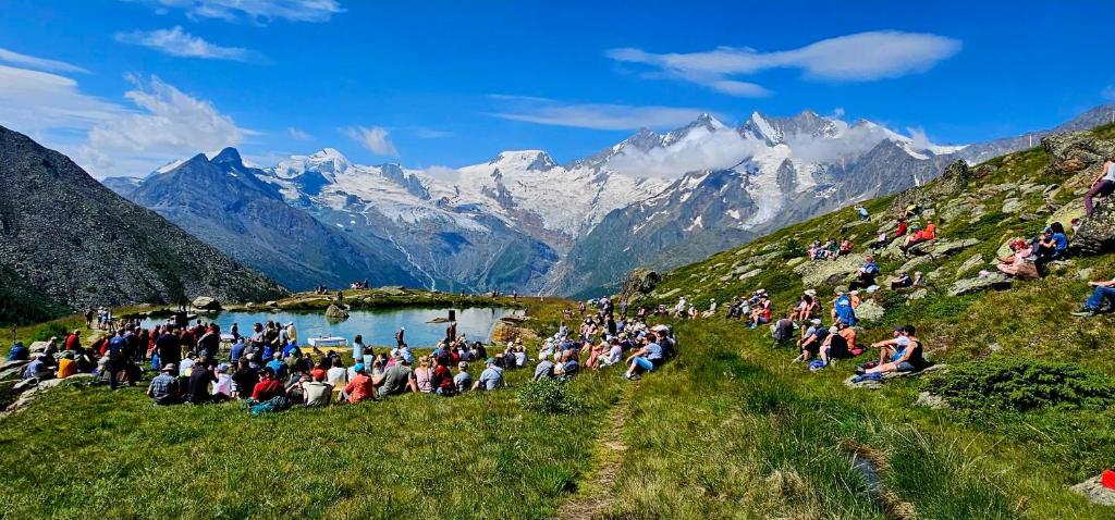 a crowd of people on a hill with mountains in the background at Sunshine in Saas-Grund