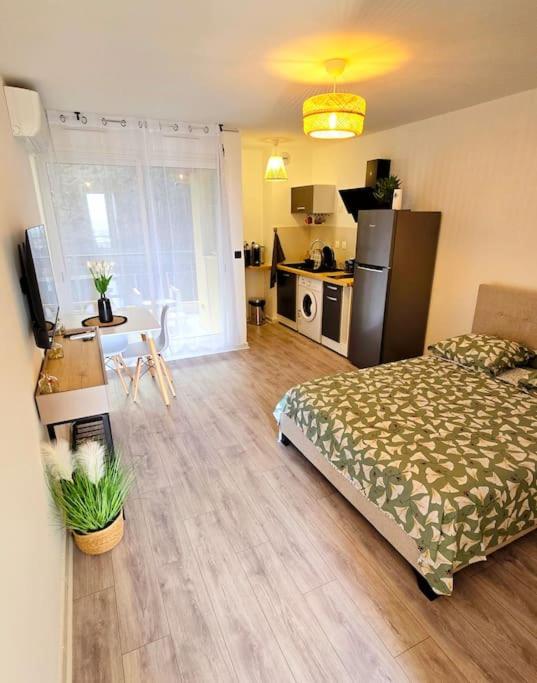 a bedroom with a bed and a kitchen with a table at Élégant studio Les Tourtereaux in Saint-Denis