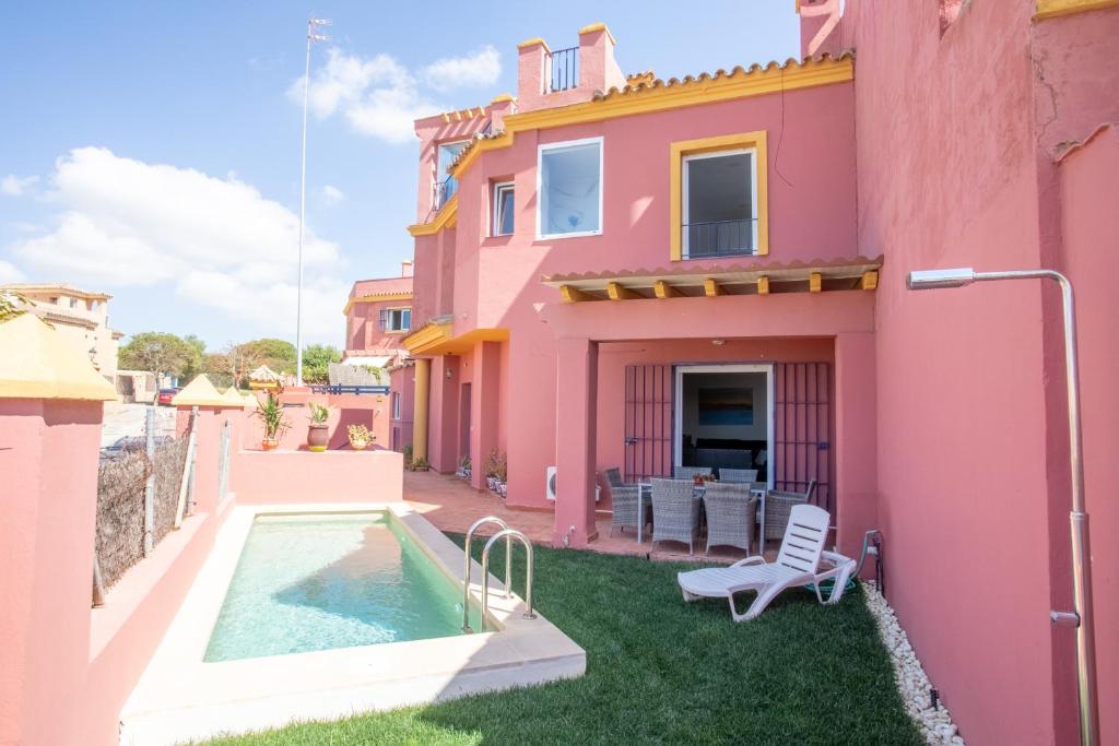 a pink house with a swimming pool in the yard at Wehost-costaluz Casa Guayaba con piscina privada in El Puerto de Santa María