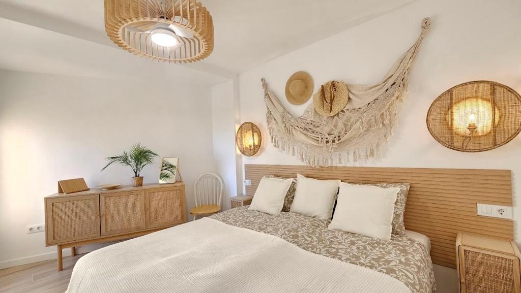 Un dormitorio con una cama con sábanas y almohadas blancas. en Boho Arenal Bol, en Calpe