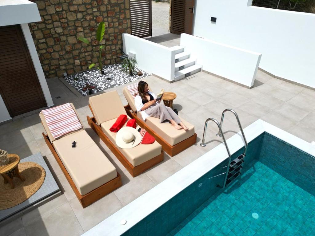 a woman sitting in a chair next to a swimming pool at Valantina's & Mannouel Lardos Luxury Villas in Lardos