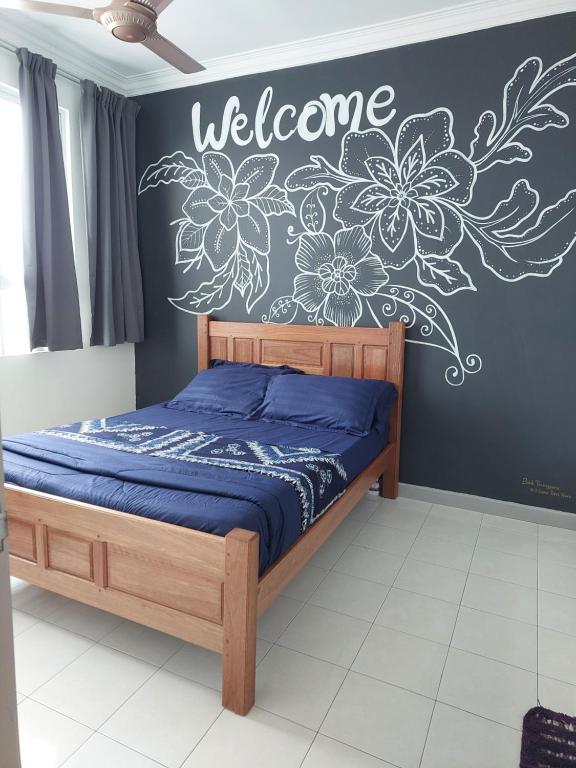 een slaapkamer met een bed met een welkomstbord aan de muur bij #dganuresthouz Kuala Terengganu, Malaysia in Kuala Terengganu