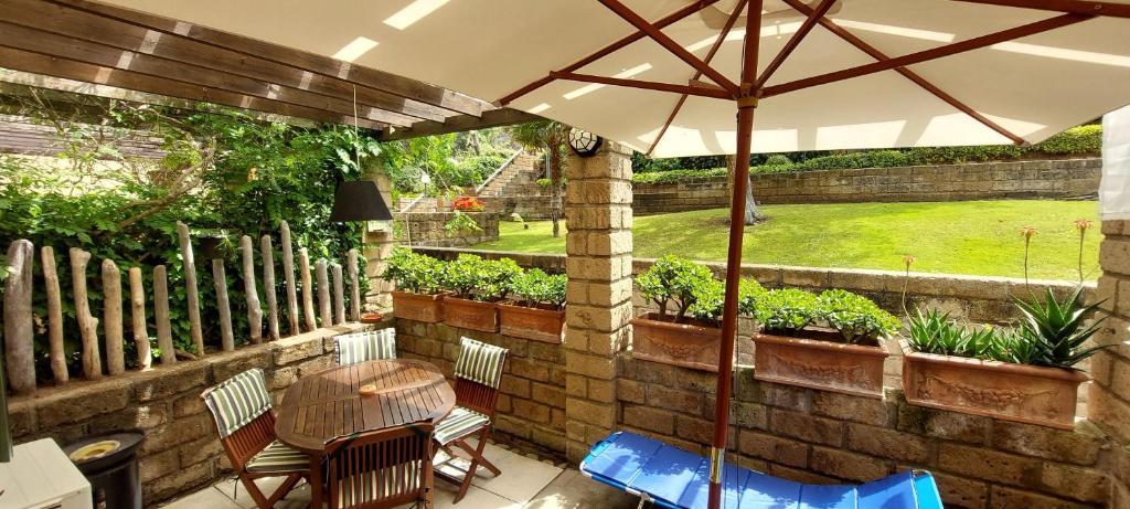 patio con tavolo, sedie e ombrellone di Confortevole Bilocale Giardino Doppio Parcheggio a Punta Ala