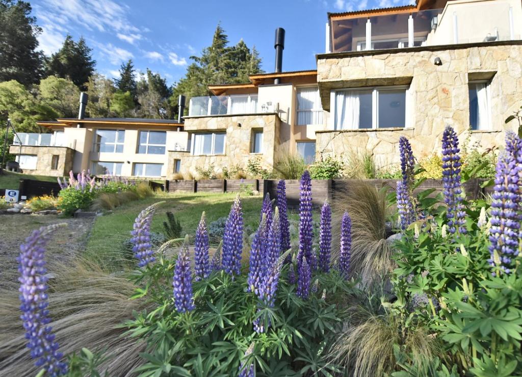 een tuin met paarse bloemen voor een gebouw bij Cuesta de los Andes By Visionnaire in San Martín de los Andes